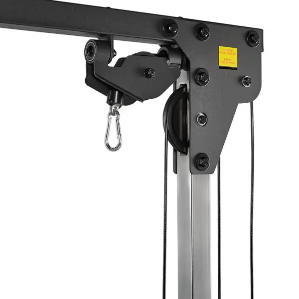 Close-up of an ATX® Cable Crossover 500 198cm in black and silver, showcasing its sturdy pulley system with ropes, metal hook, multiple bolts, and a small yellow sticker with red text on the upper section.