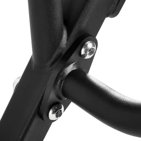 Close-up of a black metal frame with three shiny silver bolts securing two intersecting bars, reminiscent of a trap bar. The surface has a matte finish, and the image emphasizes the sturdy construction and minimalist design of the structure.