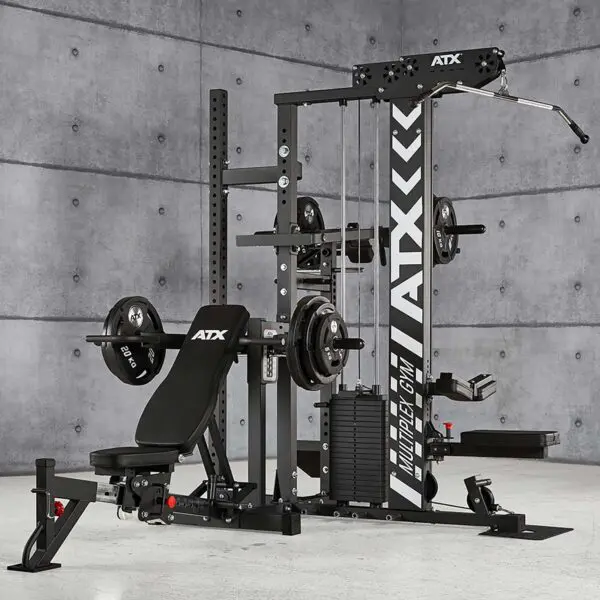 The ATX® MultipleX Multi Gym - 700 is a multifunctional home gym set with a bench, weight plates, pulleys, and pull-up bar. It features a black design with ATX branding against a gray concrete wall in a spacious room.