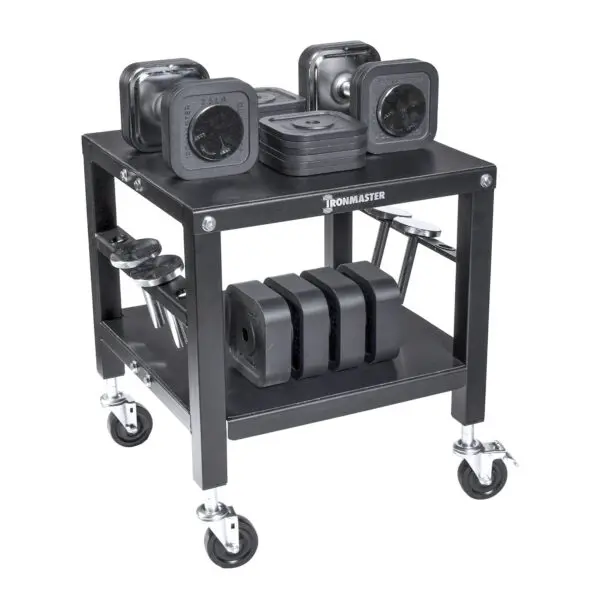 The Ironmaster QLDB Stand PRO is a black, wheeled cart with two shelves and a sturdy metal frame. It holds square Ironmaster adjustable dumbbells, while barbells are neatly organized on the sides.