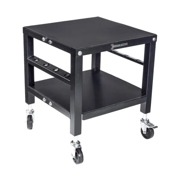 The Ironmaster QLDB Stand PRO is a sturdy black equipment cart with a square design, featuring a flat top surface for adjustable dumbbells, a lower shelf, four swivel casters for easy mobility, and a side rack for accessory storage.