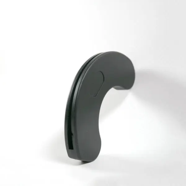 A black, curved object identified as a Dumbbell Handle Seat stands upright on a white surface against a plain white background in a minimalist, abstract shape.