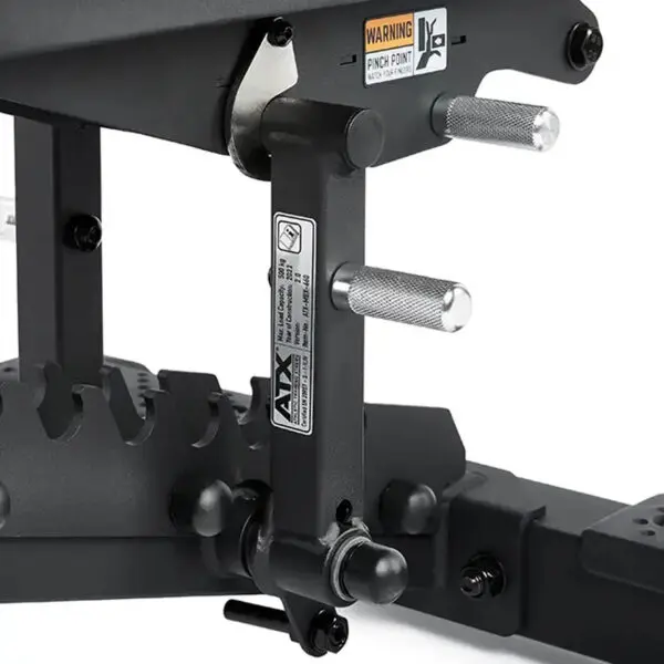 Close-up of the ATX® Commercial FID Bench ATX-MBX-660 mechanism with metal handles and a warning label. The matte black finish and adjustable bolts ensure stability for strength training, making it ideal for use with a flat incline bench setup.
