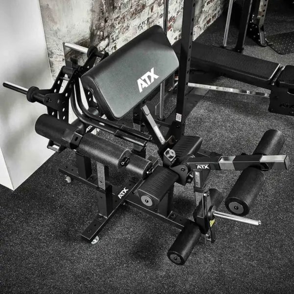The ATX® Attachment Storage Rack, with padded rollers and adjustable settings, is placed on a carpeted floor against a brick wall.