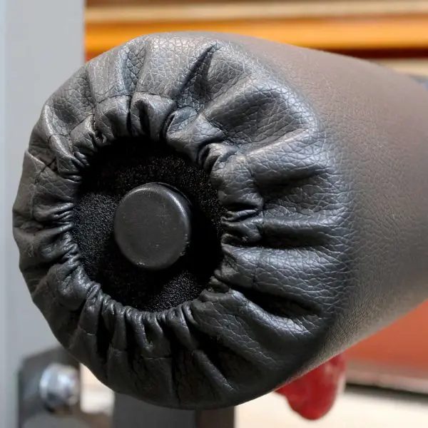 Close-up of the Foam Roller Cover 65mm in black leather, with a central black button and gathered stitching. A slightly blurred background emphasizes focus on the cushion roll.