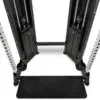 Close-up view of a dual adjustable pulley gym machine with weight stacks and a footplate. The metal frame has multiple adjustment holes and cable pulleys on each side, set against a white background.