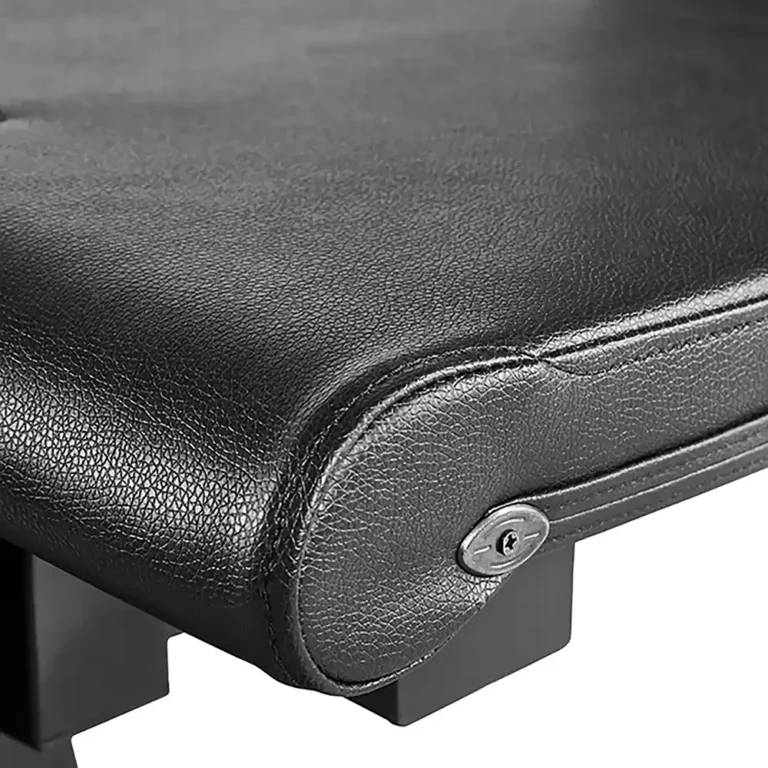 Close-up of the corner of a padded black leather bench from the ATX Leg Extension Leg Curl Machine, with visible stitching and a metal screw on the side. The detailed leather texture and sturdy structure feature a sleek black base.