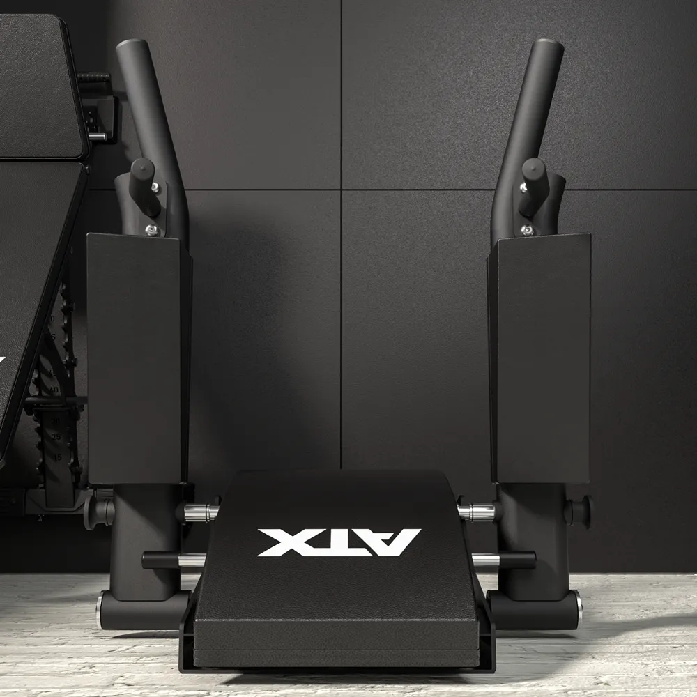 The ATX® Wall Mounted Knee Raise & Dip, finished in black and featuring angled handles and robust padding, is mounted against a black tiled wall on a light wooden floor—ideal for exercises such as knee raises, dips, and other upper body workouts.