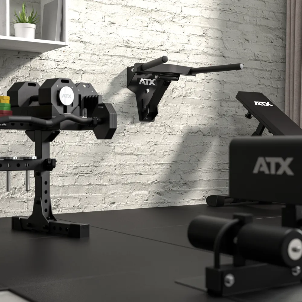 Modern home gym featuring black ATX® Folding Wall Mounted Dip Handles, an adjustable bench, weights, and a white brick wall in the background. Shelves with decor can be seen on the upper left.