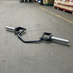 A hex bar with a black frame and silver handles resembling the ATX® Olympic Hammer Curl Bar DISCONTINUED, labeled 10 KG and ATX, lies on a concrete floor. In the background, pallets of boxes and equipment are neatly stacked.