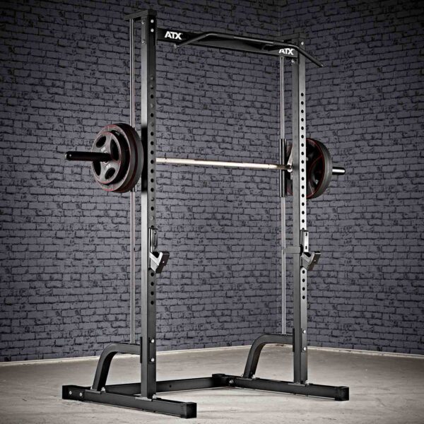 The ATX® Smith Machine Half Rack is positioned against a textured gray brick wall with a barbell and weights. The concrete floor enhances the gym-like ambiance.