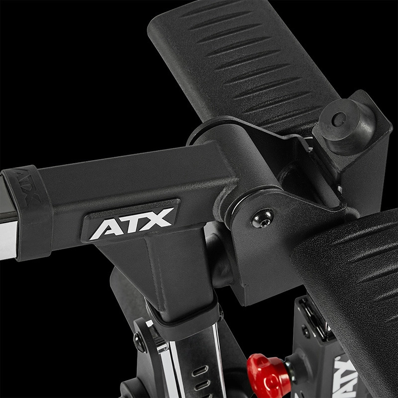 Closeup of the ATX Leg Extension/Leg Curl Attachment, a black fitness machine component with textured handles, adjustable settings, and a red knob, set against a black background.