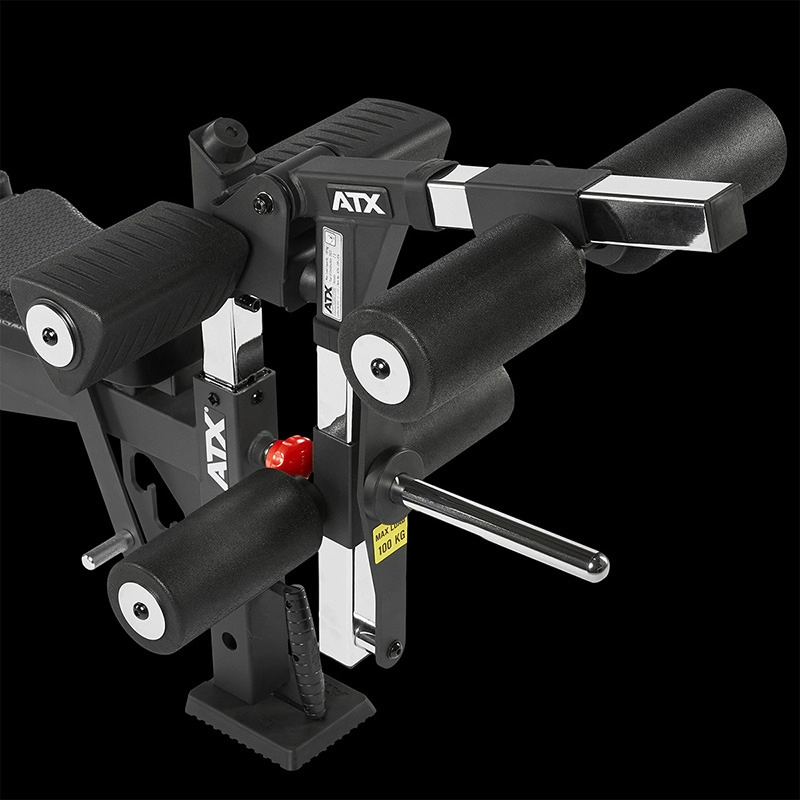 Close-up of the ATX Leg Extension/Leg Curl Attachment in black, featuring padded rollers, metal components, adjustment levers, and a weight pin, shown against a black background.
