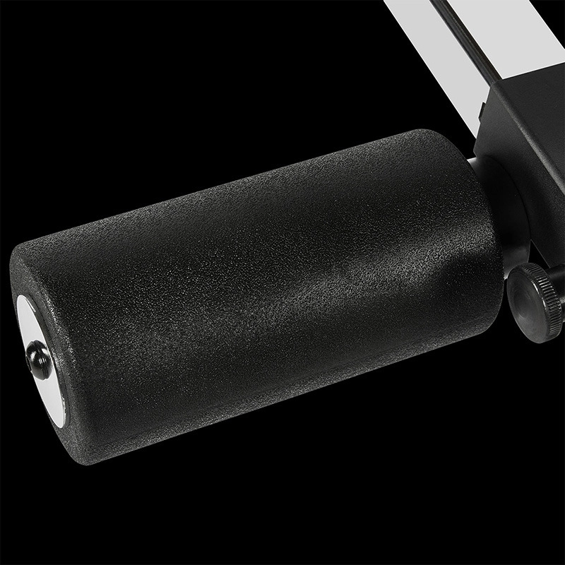 Close-up of the ATX Leg Extension/Leg Curl Attachment featuring a black foam roller on a metal bar, designed for gym equipment, shown against a black background.