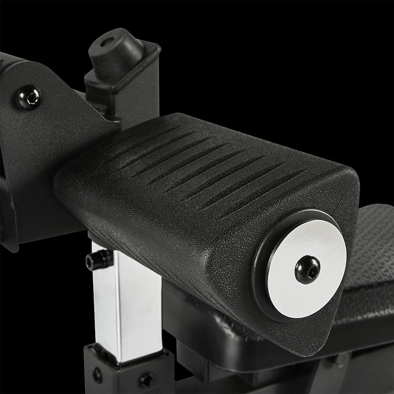 Close-up of the ATX Leg Extension/Leg Curl Attachment’s black padded armrest with a textured surface, attached to a metal support structure and featuring a side circular metal detail, shown against a black background.