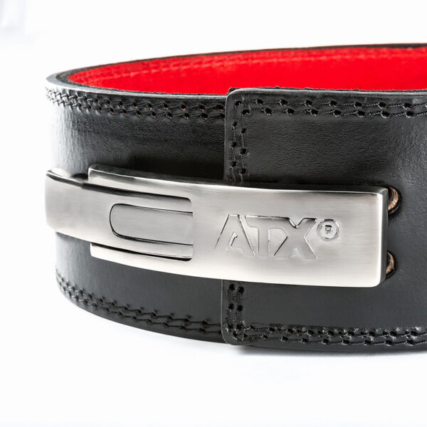 Close-up of the ATX® Lever Leather Powerlifting Belt, featuring a black leather design with a shiny silver buckle engraved with the ATX logo. The belt's inner lining is red, with visible stitching along the edges. The focus is on the buckle and the texture of the leather.