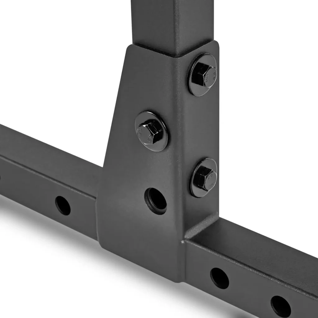 Close-up of the ATX® Power Rack 520 215cm, showcasing a black matte metal frame with intersecting bars secured by three large bolts. One bar features holes for adjustable positioning.