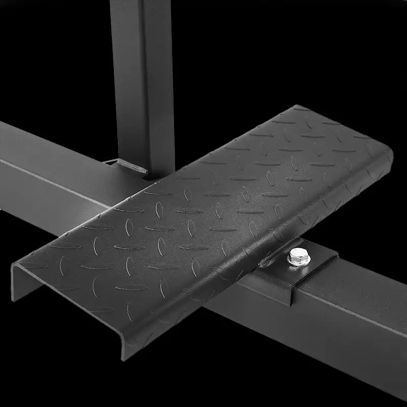 Close-up of the textured metal footplate on the ATX Seated Calf Raise Machine, attached to a black frame with a bolt. The diamond tread pattern provides extra grip, set against a sleek black background.