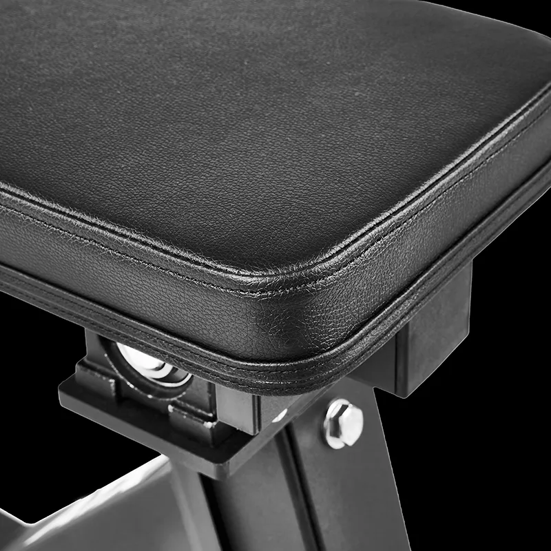 Close-up of the corner of the black padded bench seat from the ATX Seated Calf Raise Machine, showing visible stitching and part of the metal frame against a plain black background.