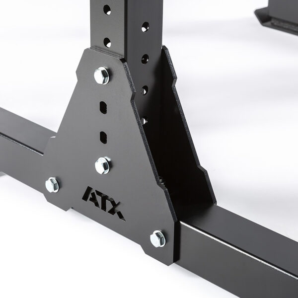 Close-up of a black metal frame with multiple bolts and perforated holes, labeled ATX® Bulls Strongman Yoke DISCONTINUED at the base. The structure resembles gym equipment like a yoke or squat rack, providing robust support against a plain white background.