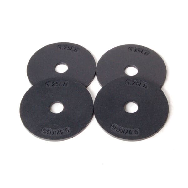 Four black weight plates, each labeled 1.25 LB, are arranged in a square pattern on a white backdrop, enhancing the sleek Ironmaster Heavy Handle Kit design.
