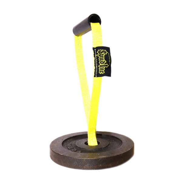 The Spud KettleStrap Kettlebell Strap features a cylindrical grip handle secured to a fluorescent yellow strap, which is mounted on a round, black weight plate. The strap also includes a fabric tag with the logo.