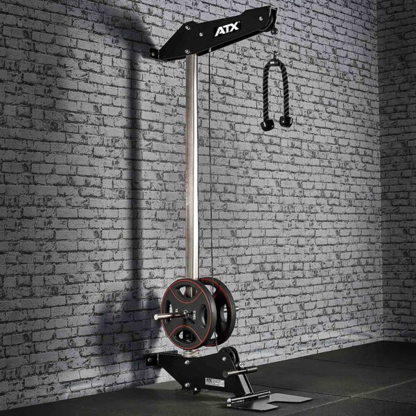 The ATX® Wall Mounted Lat Pulldown boasts a sleek black metal frame, weight plates, and a double-handle grip. It is ideally positioned against a textured gray brick wall in a gym setting, providing both functionality and style for an intense workout experience.