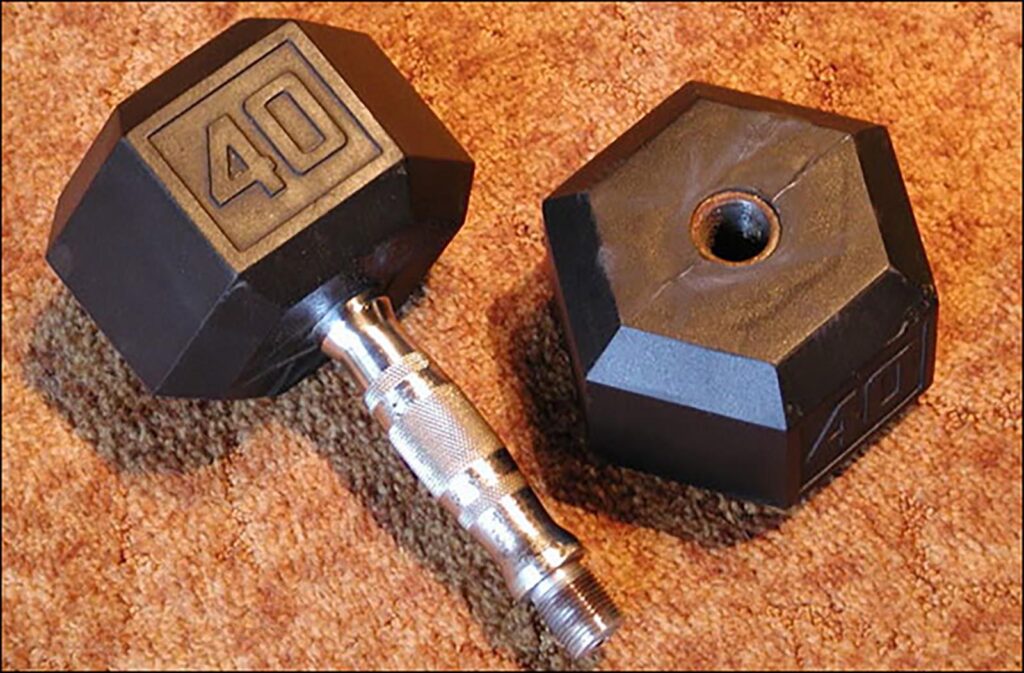 A 40-pound hex dumbbell with rubber ends is shown. One end is detached, revealing a threaded metal handle. The equipment is placed on a textured brown carpet.