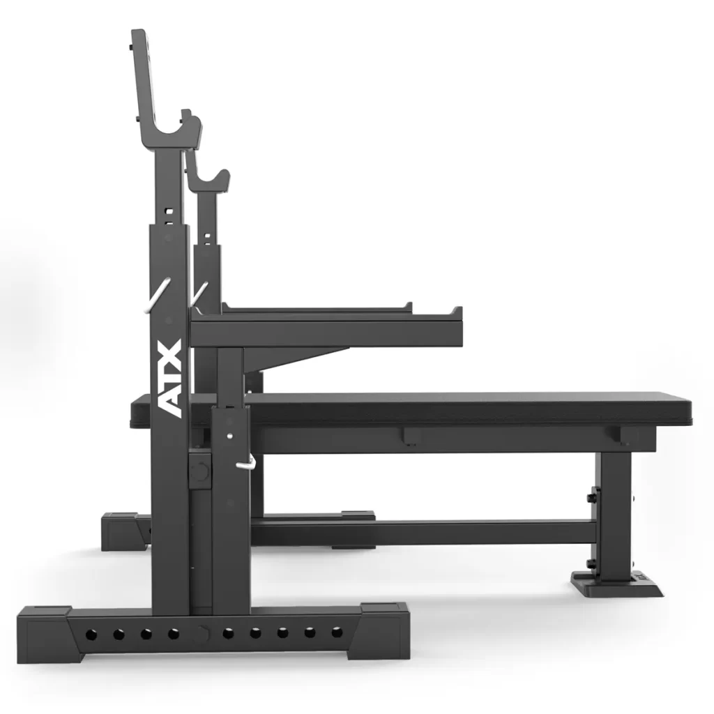 The ATX® Olympic Bench Press 700 features a side view of a black weightlifting bench with adjustable barbell racks, showcasing a robust metal frame and ATX on the side, all set against a plain white background.