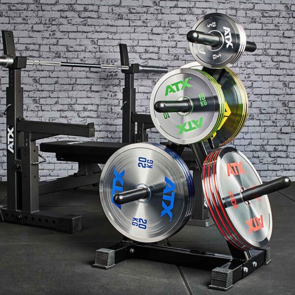 A gym setup with a weight bench and rack displaying ATX® 25kg Chrome Powerlifting Single Plates, against a brick wall backdrop and black gym matting on the floor.