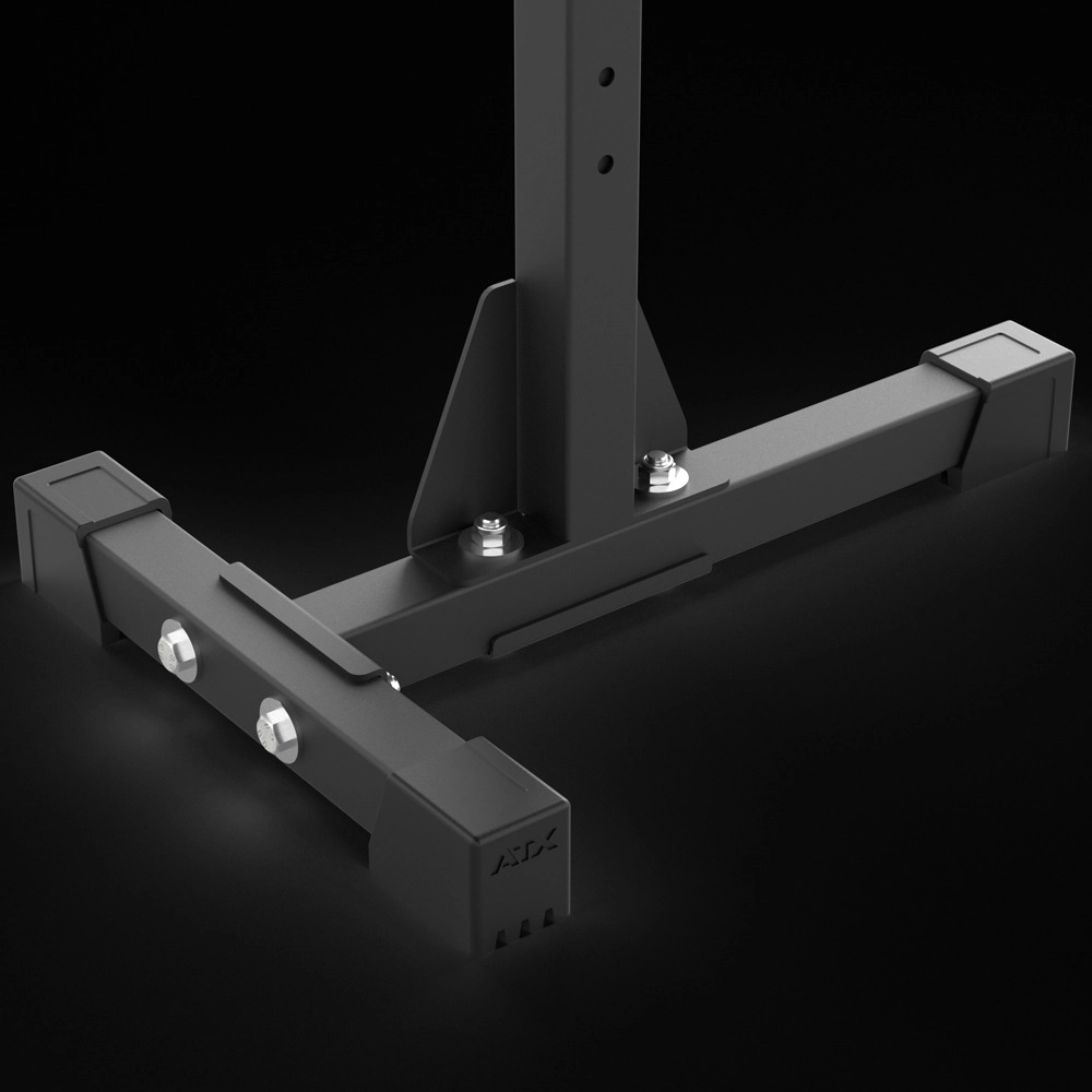 Close-up view of the sturdy black metal base with bolts and a vertical support beam, part of the ATX® Squat Stands 510, designed for home gym use, set against a dark background.
