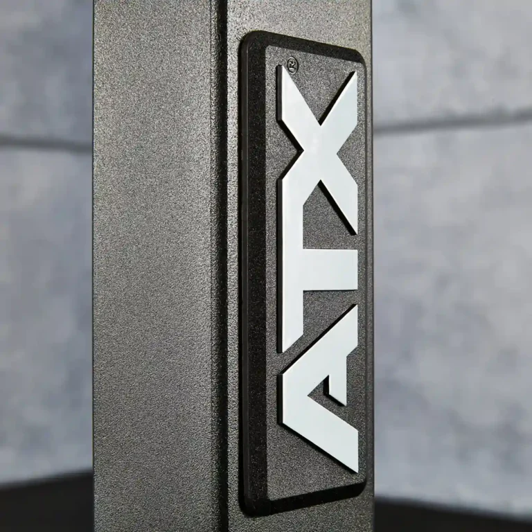 Close-up of a metal surface featuring the logo ATX in bold white letters on a black rectangular background, reminiscent of high-quality gym equipment like a ghd machine. The background is out of focus.