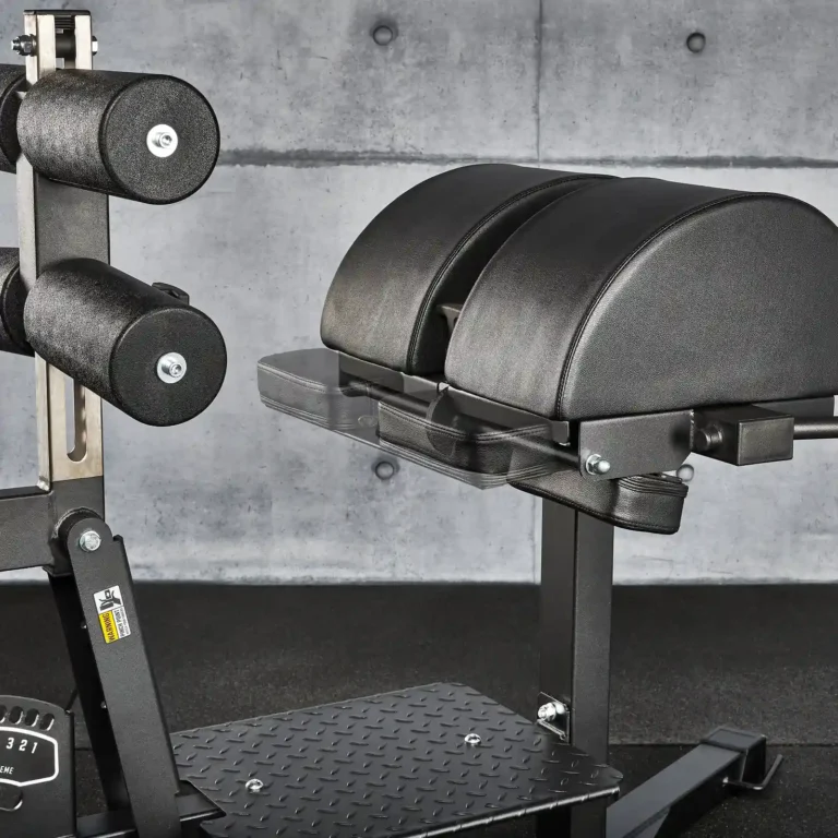 A sleek black GHD machine with padded supports and metal components, designed for back extension exercises. It's set against a textured concrete wall in a fitness facility, enhancing the glute extension workout experience.