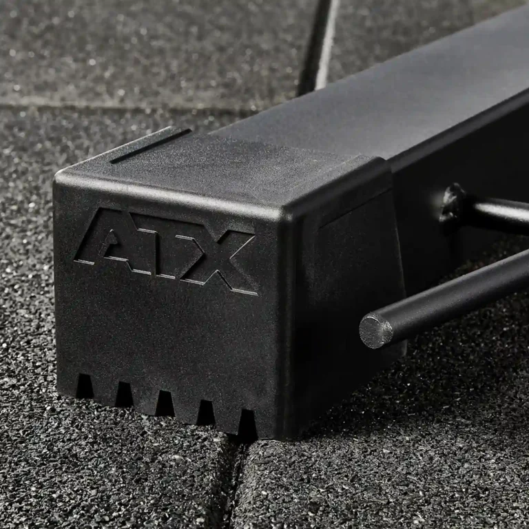 Close-up of a black ATX weightlifting piece, possibly a glute and ham raise machine, featuring sturdy, textured construction on a rubber gym floor. The ATX logo is embossed on the side.