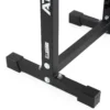 The ATX® Split Squat Stand features a close-up view of its black metal frame with bolts and logo, supported by rubber footings on a white surface. Its design suggests stability and durability.