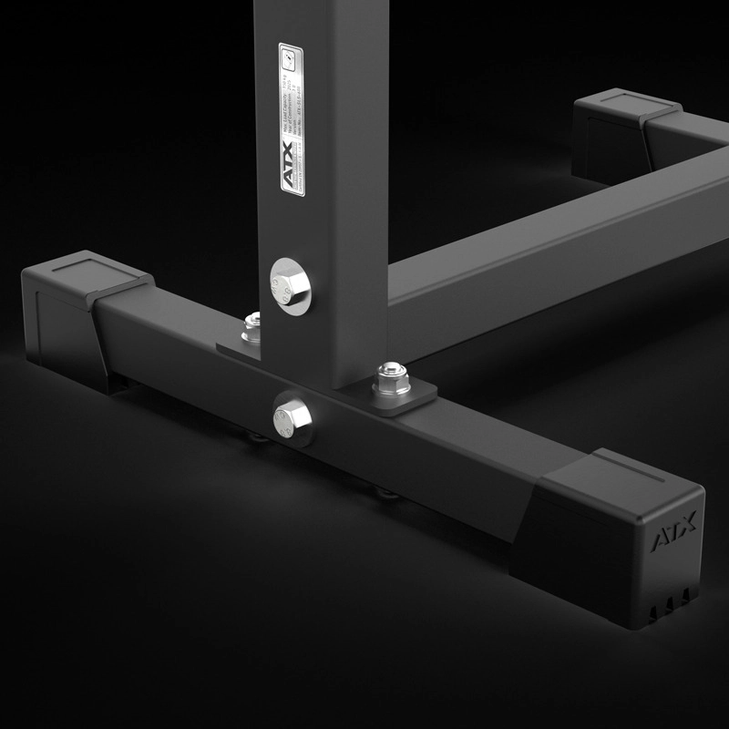 Close-up of the base of the ATX® Split Squat Stand metal frame featuring bolts, a pillar, and black foot caps against a dark background. The ATX logo appears on both the frame and the foot cap.