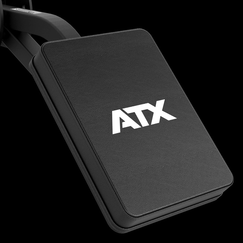 A close-up of the ATX® The Seal Row Pad—a black rectangular pad with a textured surface and "ATX" in white—attached to gym equipment against a black background.