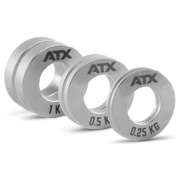 Three ATX® Olympic Fractional Plate Pairs in silver, labeled 1 kg, 0.5 kg, and 0.25 kg, are arranged in descending size with central holes for barbell placement.