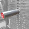 A close-up of the GymPin 2 Original inserted at the 40-lb level in a grayscale weight stack highlights its metallic pin and striking red logo. Visible weight increments range from 20 to 65 pounds, facilitating precise workout tracking.