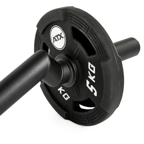 Close-up of a black FAT EZ Curl Bar weight plate labeled 5 KG, mounted on a barbell. The plate features cut-out handles for easy grip.