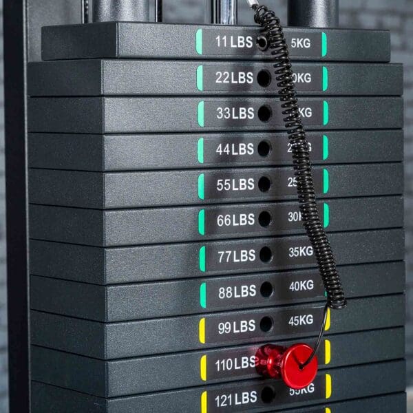 A stack of weight plates on a gym machine features Weight Stack Stickers KG/LBS. A red pin is inserted in the 77 lbs (35 kg) slot, attached with a coiled black cord.