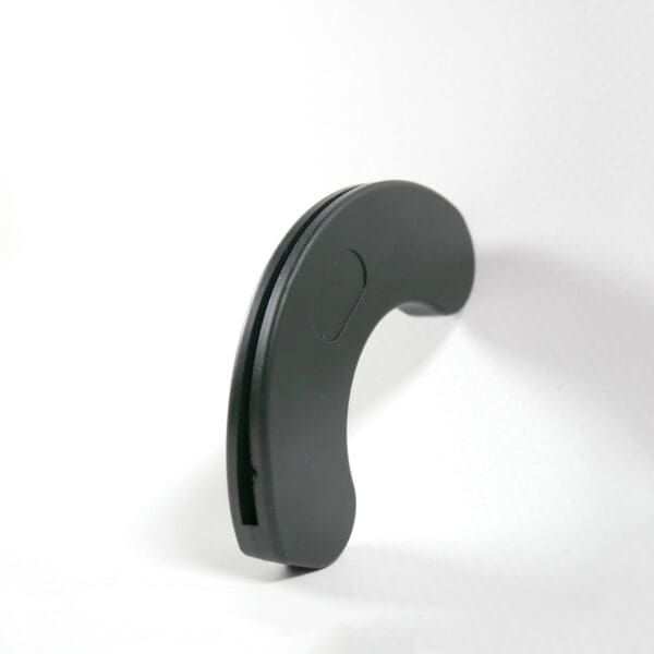 A black, curved object identified as a Dumbbell Handle Seat stands upright on a white surface against a plain white background in a minimalist, abstract shape.