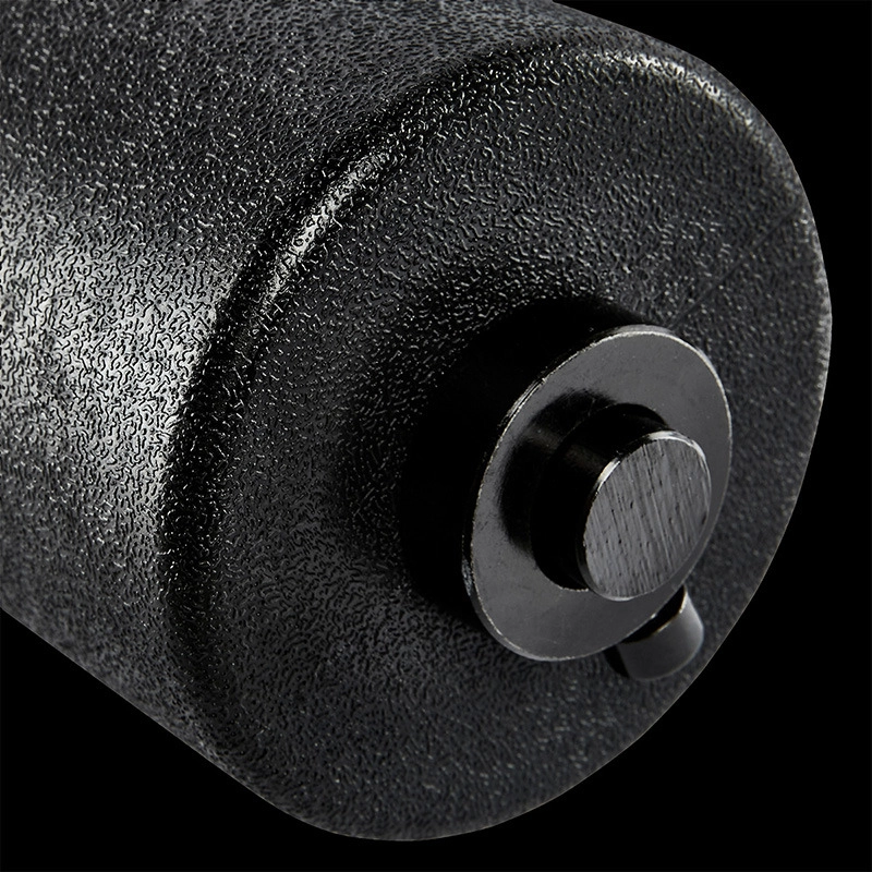 Close-up of the ATX® AB Attachment: a textured black surface with a metallic circular end cap and small protruding knob, shown against a black background.