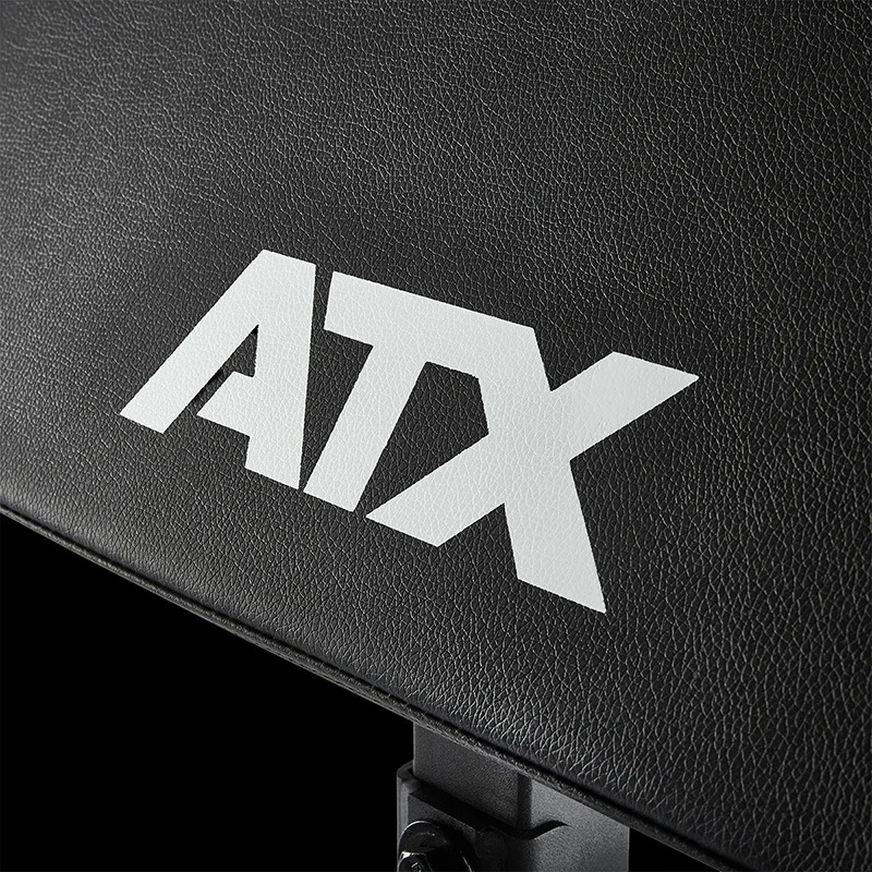 Close-up of a black textured ATX Bicep Curl Pad bench attachment featuring a white logo.