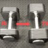 Two Ironmaster adjustable dumbbells rest on a black textured floor, with the left labeled 45 lb and the right labeled 75 lb. A red arrow points from the left dumbbell to the right, suggesting progression in your workout.