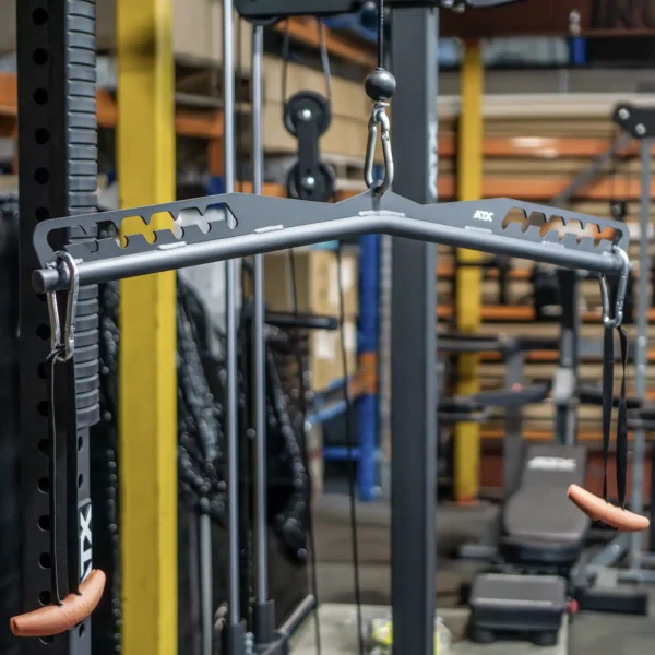The ATX Multi X Long Bar 90cm is a gym attachment for a cable machine, featuring two rubber-grip handles in a multi-grip design, amidst diverse weights and exercise gear in a fitness facility.