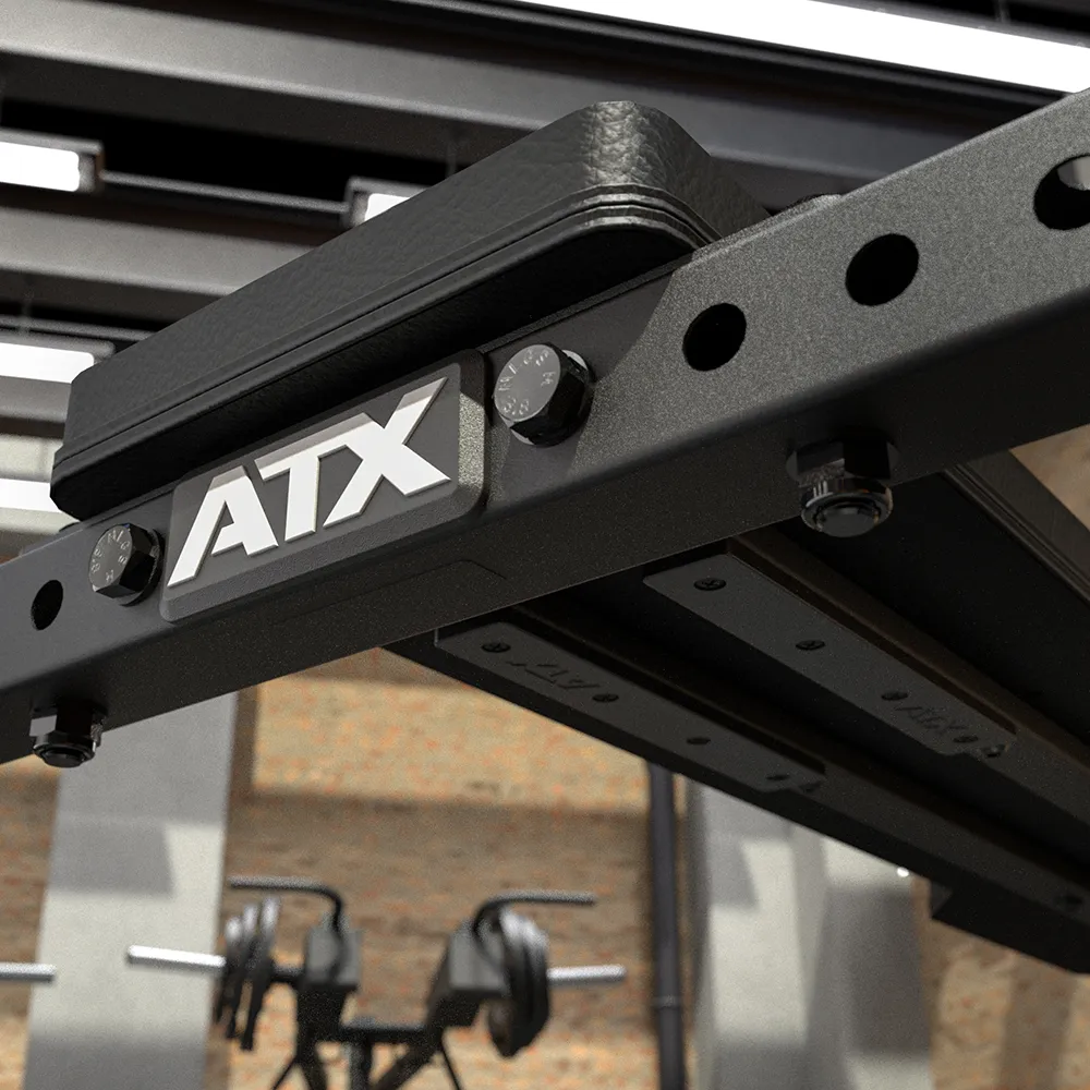 Close-up of the black ATX® Seal Row Bench with bolts, adjustment holes, and the ATX logo, set in a gym featuring barbells and brick walls in the blurred background.