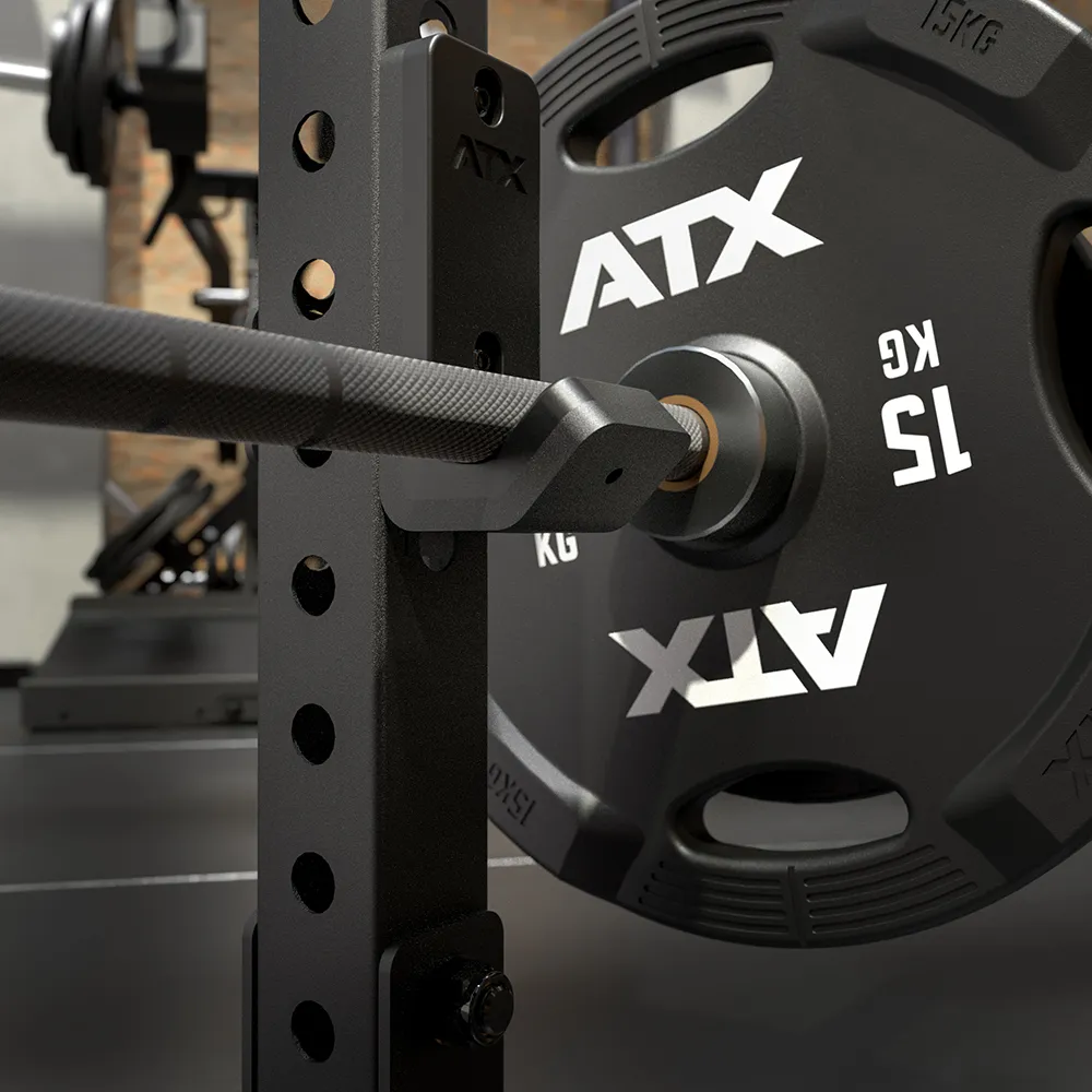 Close-up of an ATX® Seal Row Bench featuring a barbell loaded with a 15 kg ATX weight plate, set up in a gym with blurred equipment visible in the background.