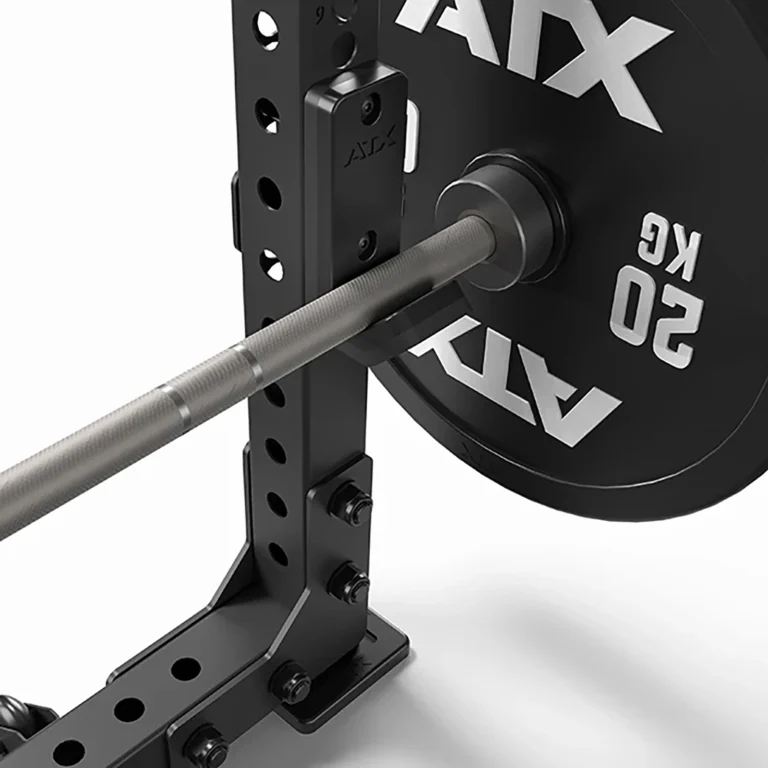 Close-up of a barbell with a 50 kg weight on a rack next to an ATX® Seal Row Bench. The sleek black metallic rack has adjustable holes for various height settings.