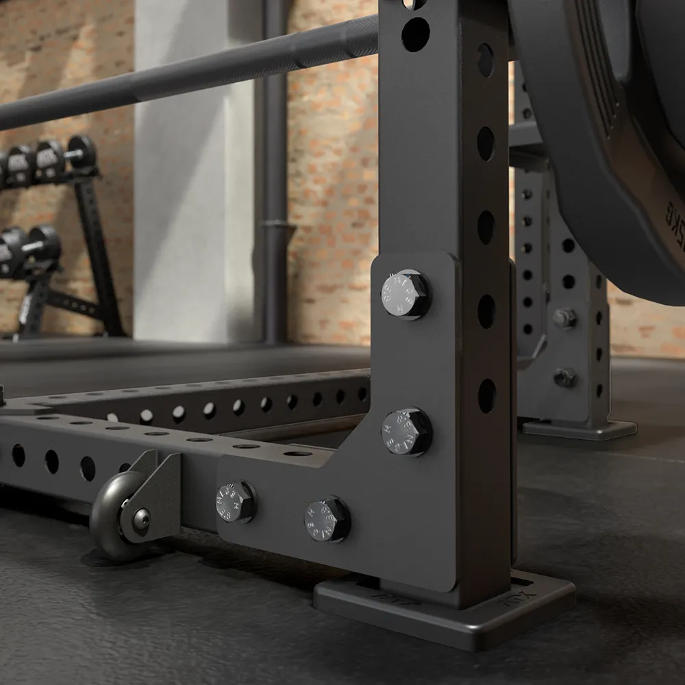 Close-up view of the ATX® Seal Row Bench in a gym, featuring a heavy-duty black metal frame, weights loaded on a barbell, dumbbells organized on a rack, and an exposed brick wall in the background.